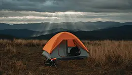 Group of people enjoying a camping trip outdoors, surrounded by nature, with tents set up in the background.