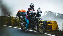 Motorcyclist riding through scenic roads during a touring adventure, with open landscapes in the background.