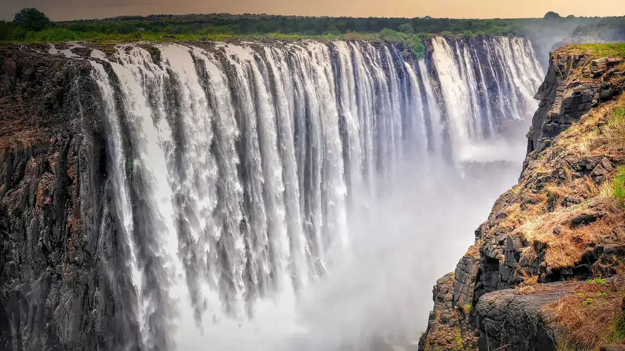 Victoria Falls in Zimbabwe and Zambia, one of the most breathtaking places to visit in Africa, with cascading water and mist rising above lush green surroundings.