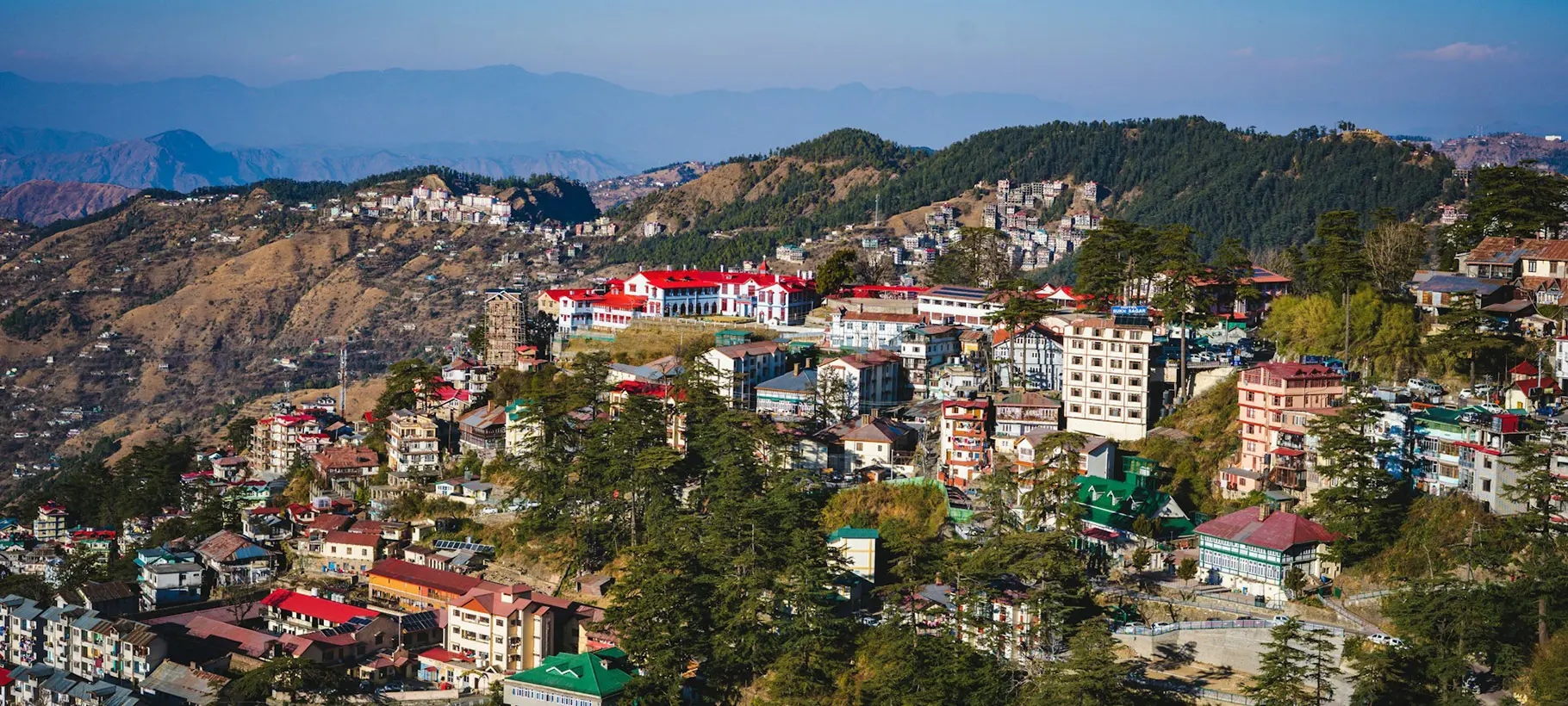 Picturesque view of Shimla town nestled in the Himalayas, featuring colonial architecture and lush green hills.