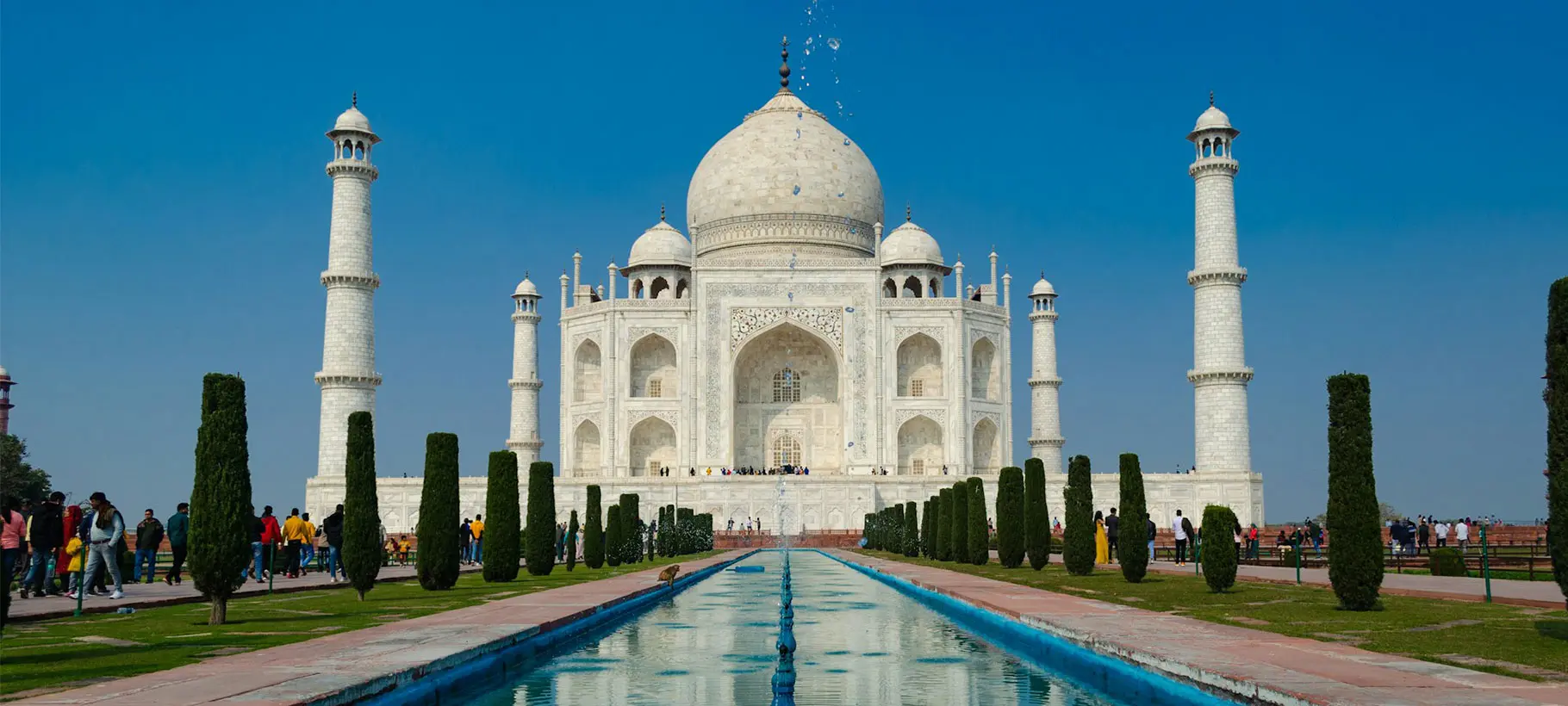 The iconic Taj Mahal mausoleum in Agra, India, with its white marble domes and minarets reflecting in the water.