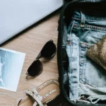 Travel tips displayed with a suitcase, passport, and travel accessories on a wooden table
